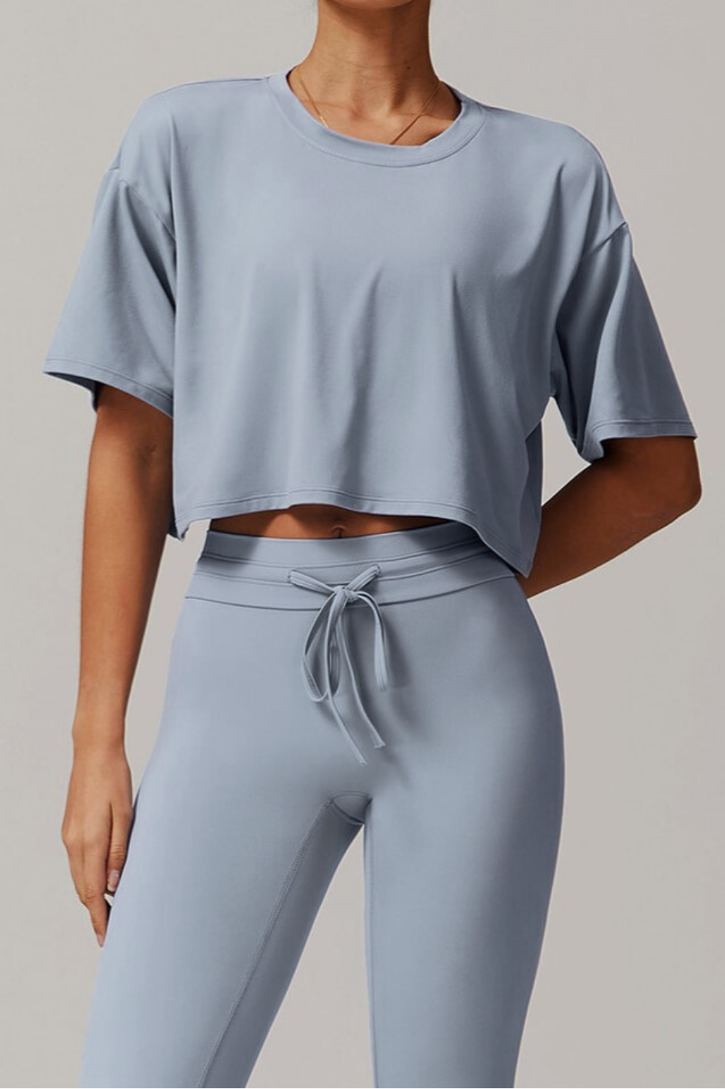 Person wearing a light blue grey athletic outfit on a neutral background