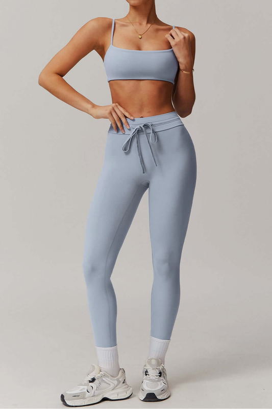 Person wearing a light blue grey athletic outfit on a plain background