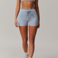 Person wearing a light blue grey sports bra and shorts set on a plain background