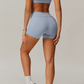 Person wearing a light blue grey sports bra and shorts set on a neutral background